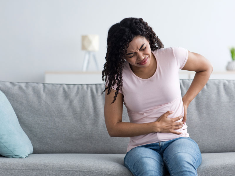 woman in agony holding stomach and back to illustrate chronic pain