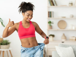 African lady celebrating loose jeans round waist to illustrate semaglutide weight loss