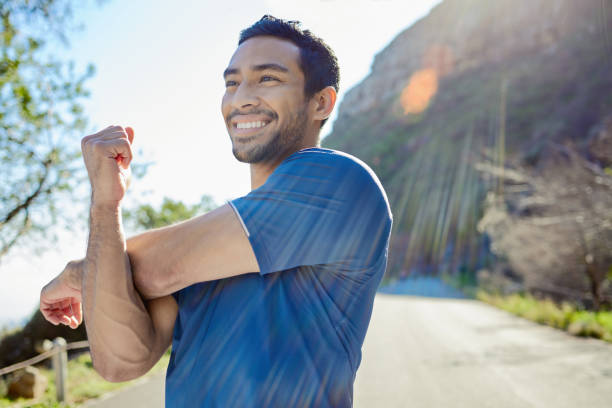 Young man stretches beside a road before a run without pain